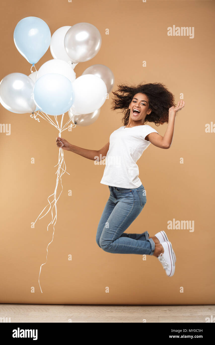 Full length portrait of a cheerful young african woman jumping while ...