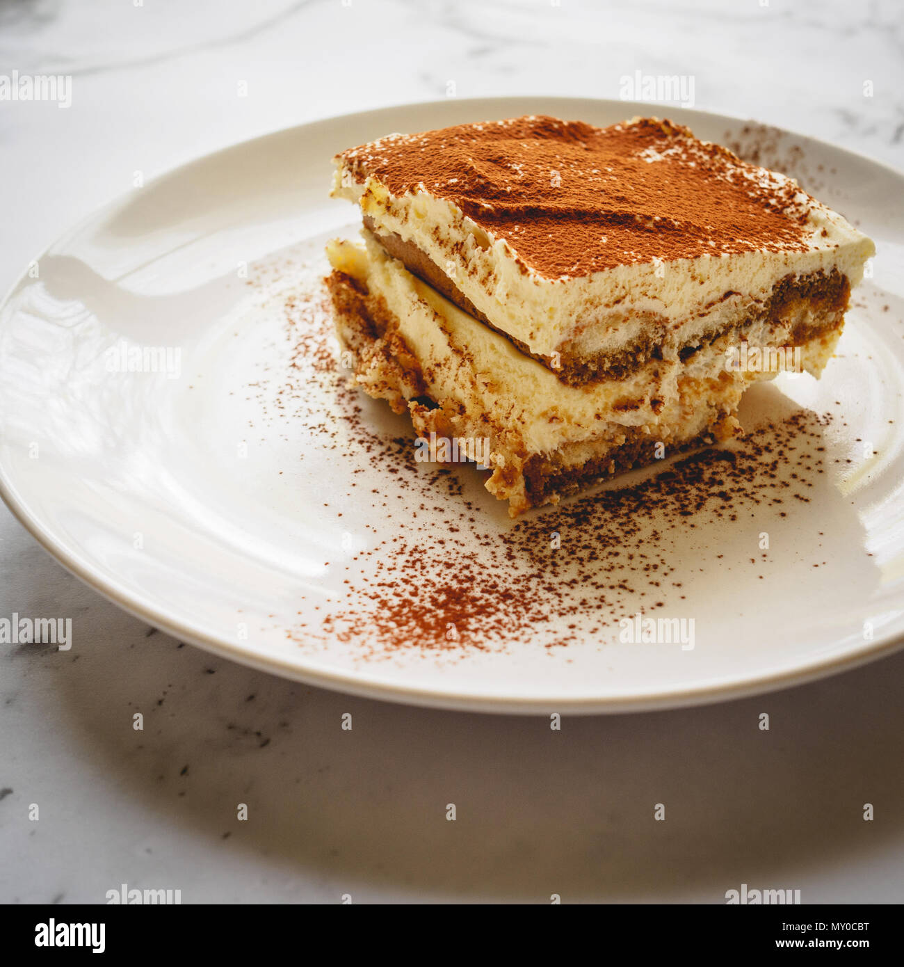 Close Up Of A Slice Of Homemade Tiramisu Traditional Italian Dessert On A White Plate With A Spoon On A Marble Board Square Format Stock Photo Alamy