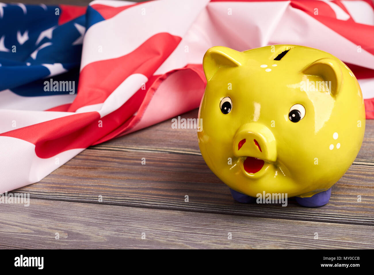 Close up yellow piggy bank and USA flag. American national flag and money box on wooden background. Budget and savings. Stock Photo