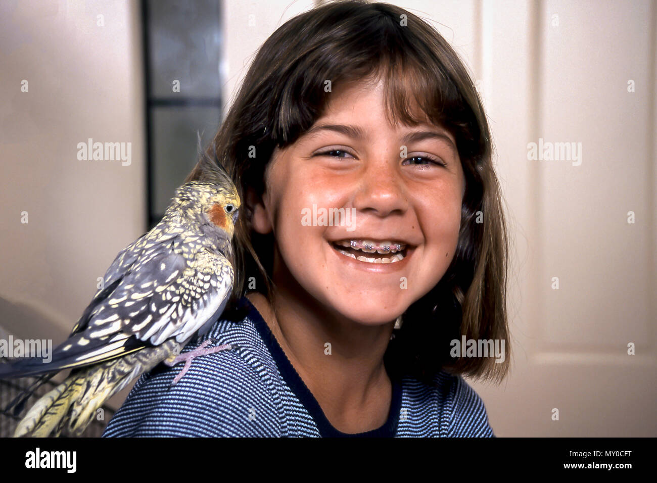 Young Girl laughs at pet bird sitting on her shoulder. MR. © Myrleen