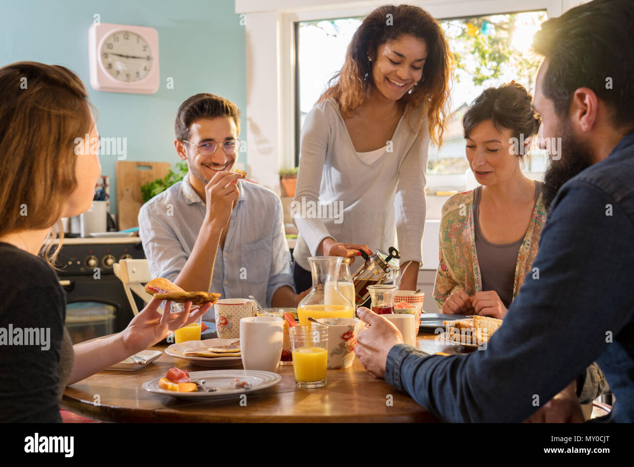 bunch of multi-ethnic friends gathered around a table for breakf Stock Photo