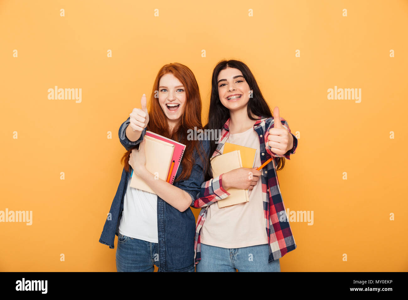 Portrait of two happy young school teenage girls holding copybooks and ...