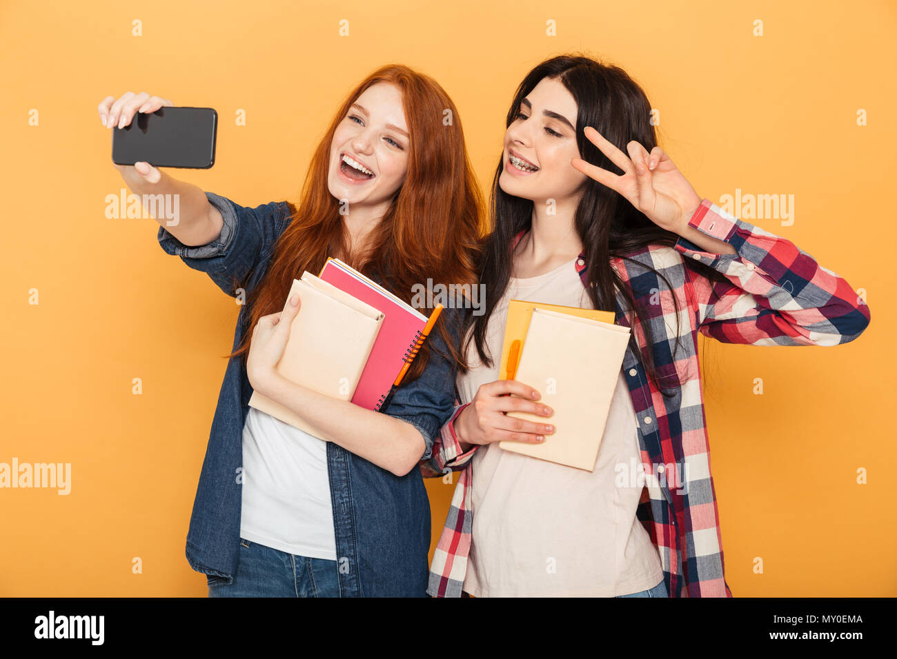 Portrait of two pretty young school teenage girls holding copybooks and ...