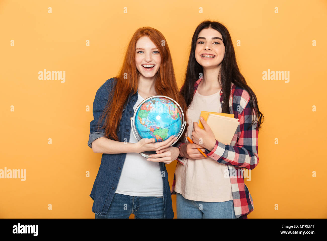 Portrait of two joyful young school teenage girls holding copybooks and ...