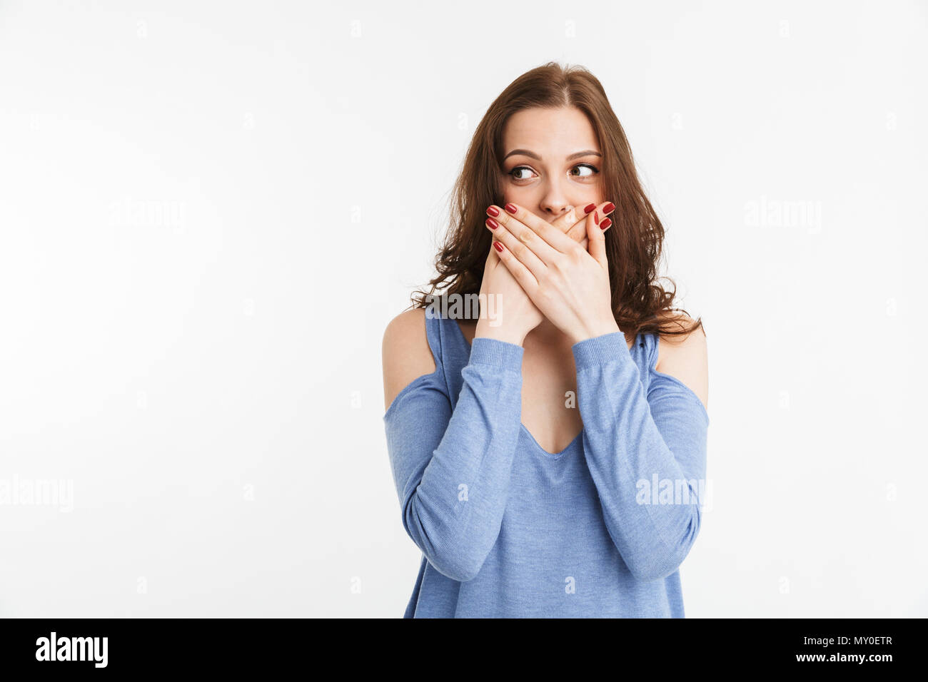 Portrait of a shocked young woman covering mouth with hands isolated ...