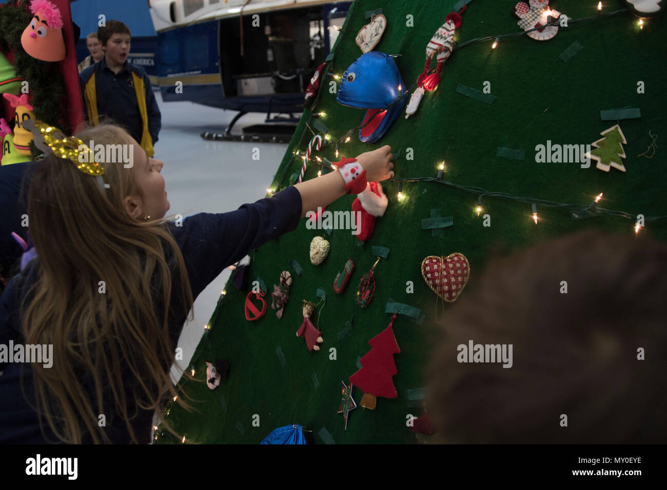 Children decorate a holiday tree with ornaments during the 2016 Parents and Children Fighting Cancer Christmas Party at Joint Base Andrews, Md., Dec. 10, 2016. The tree was later used in a puppet show performed by the Berryville Baptist Rascals.  The JBA Fisher House has sponsored the event for 29 years. (U.S. Air Force photo by Airman 1st Class Rustie Kramer) Stock Photo