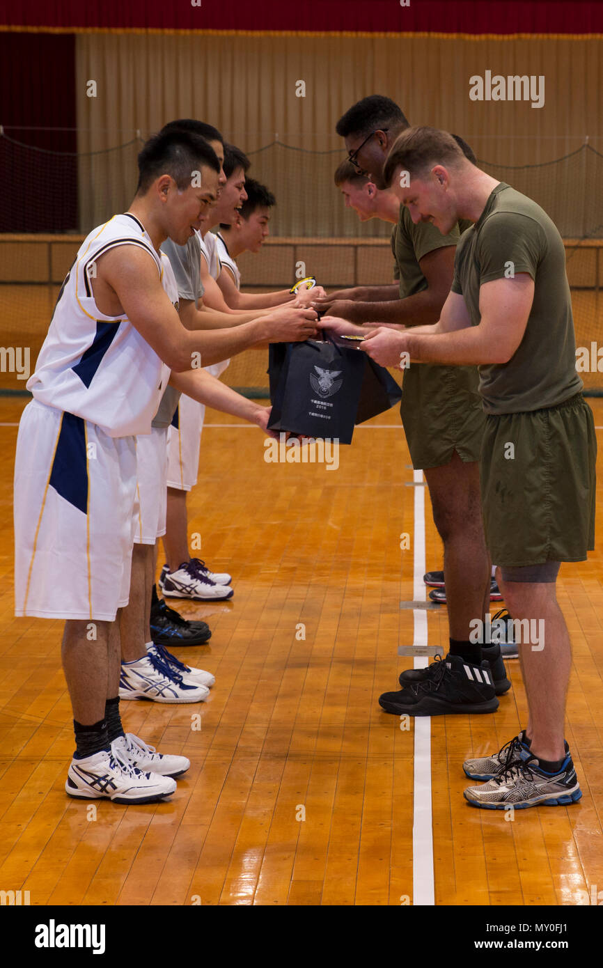 U.S. Marines with Marine Attack Squadron (VMA) 542, trade patches and gifts  after a game of basketball with players of the Japan Air Self-Defense Force  basketball team during the Aviation Training Relocation