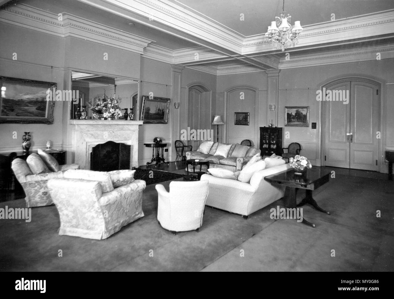 View of Government House, Reception Room, 11 May 1950. Johann Heussler, a wealthy Brisbane merchant purchases 22 acres of land from the Government in 1862 and made plans to build a house there. Local architect Benjamin Backhouse designed a house in 1865, to be constructed from stone excavated on site combined with a cement and lime mixture.  The Heussler family lived at Fernberg from 1865 until 1872 when the high cost of upkeep forces foreclosure on the property by the mortgagee.  Sir Arthur Palmer, Premier of Queensland (1870-1874), and later Lieutenant Governor resided in Fernberg from 1872  Stock Photo