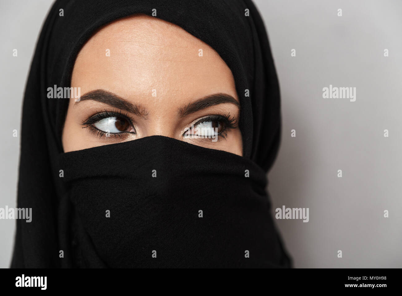 Close Up Portrait Of A Beautiful Arabian Woman Wearing Hijab Looking Away Isolated Over Gray