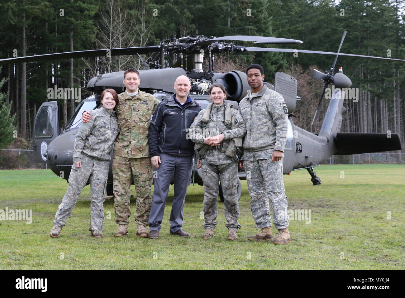 Specialist Melissa Marsolek, 1st Lt. Scott Darragh, Specialist Keely Killebrew, and Chief Warrant Officer 2 Sean Quillin, all from Charlie Company, 1st Battalion, 140th Aviation Regiment, pose for a photo with Jeff Coleman (center), aviation instructor at Emerald Ridge High School, Puyallup, Washington in front of their UH-60 Black Hawk helicopter. The visit to the high school was part of a partnership with the school's aviation program which gives aspiring pilots the chance to talk to real pilots and sit in real helicopters. Courtesy photo by Jennifer Picardo. Stock Photo