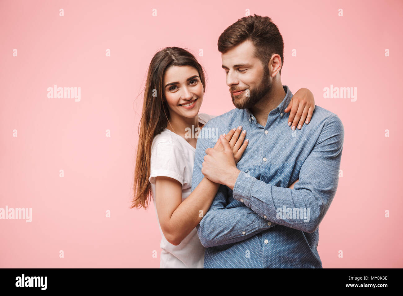 Portrait of a lovely young couple hugging while standing isolated over ...