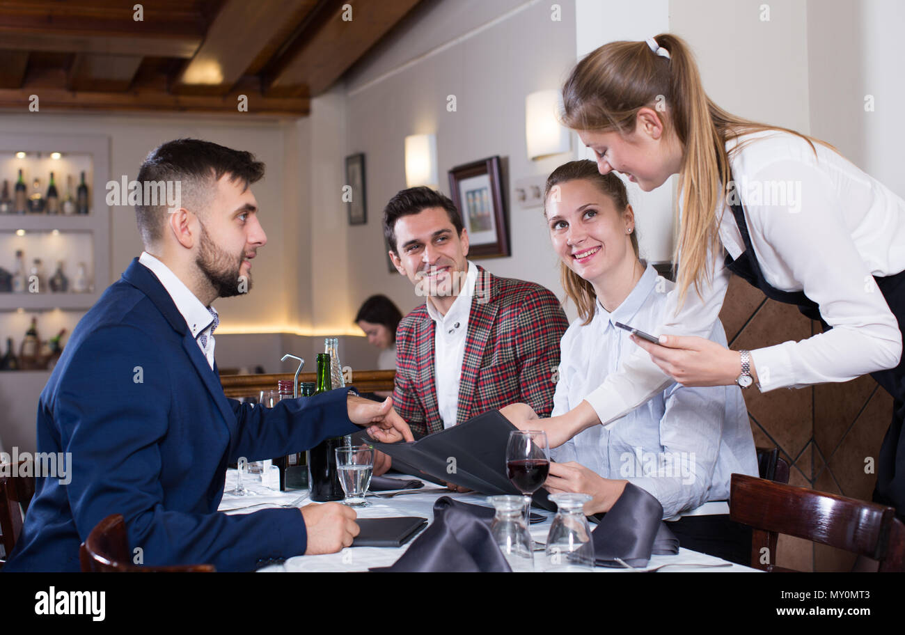 Smiling waitress taking order from guests, using digital tablet Stock Photo