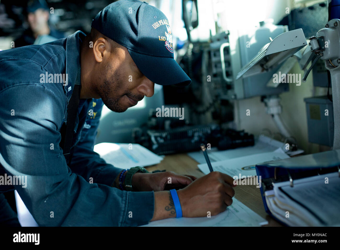 U.S. Navy Lt. j.g. Azariah D. Lishey, the officer of the deck with Auxiliary Division, Engineering Department, USS Pearl Harbor (LSD-52), writes on a perimeter sheet aboard the Pearl Harbor, Dec. 7, 2016, in the Pacific Ocean. Lishey used the perimeter sheet to determine the distance between the Pearl Harbor to another identified vessel. (U.S. Marine Corps photo by Lance Cpl. Erick J. ClarosVillalta) Stock Photo