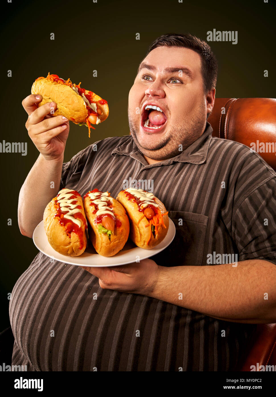 Fat man eating fast food hot dog. Breakfast for overweight person. Stock Photo