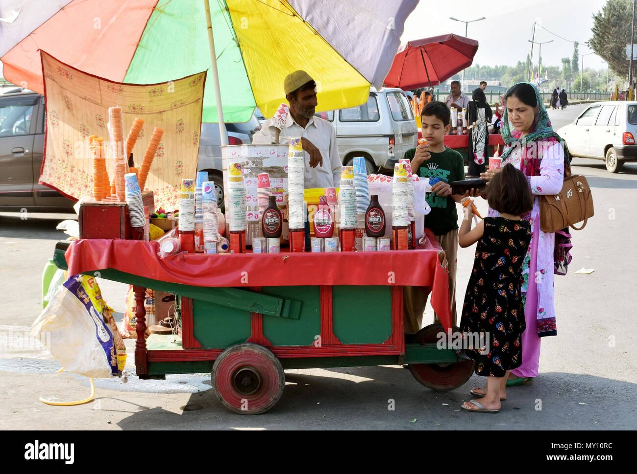 Pedestrians enjoy eating ice-cream on a hot summer day in Srinagar, Indian administered Kashmir. The heat wave continued in Srinagar city with mercury soaring above normal temperature and no immediate respite predicted by the Weather Department. The maximum temperature in the city was recorded at 34.4 degree Celsius, 8.1 notches above normal on Monday. Stock Photo