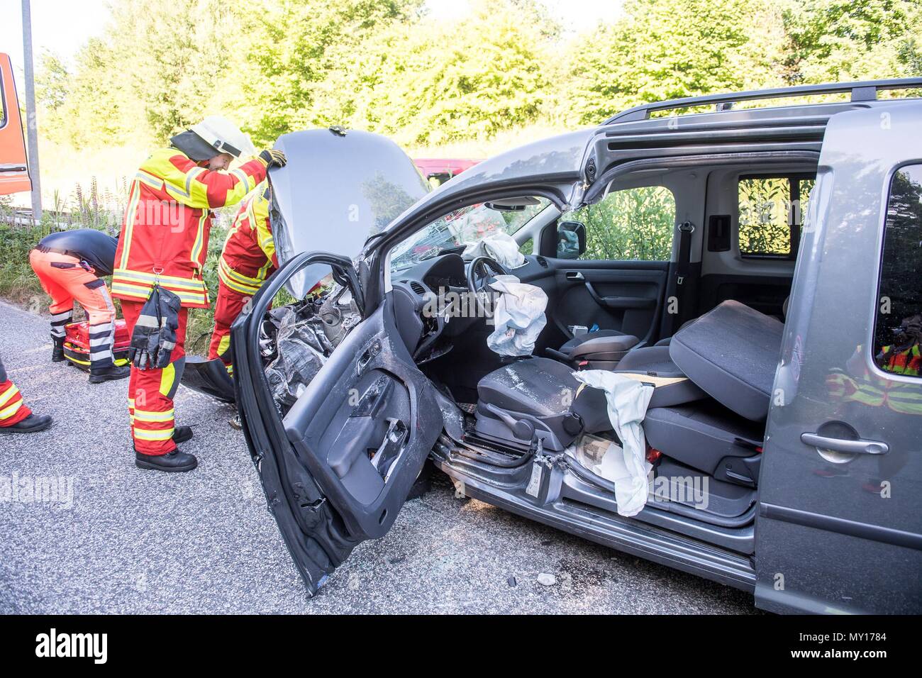 05 June 2018, Germany, Flensburg: Firefighters standing at an auto wreck. A driver circulating in the wrong direction caused several accidents, with a total of five injured, along the eastern tangent in Flensburg. Two of the injured were of gravity, according to a police spokesperson. The driver was circulating along the right direction, but he started driving in the wrong direction at a red light and rammed his car against another. Instead of stopping he is said to have turned and continued along the wrong way along the Bundesstrasse, the driving directions of which are separated by a guardra Stock Photo