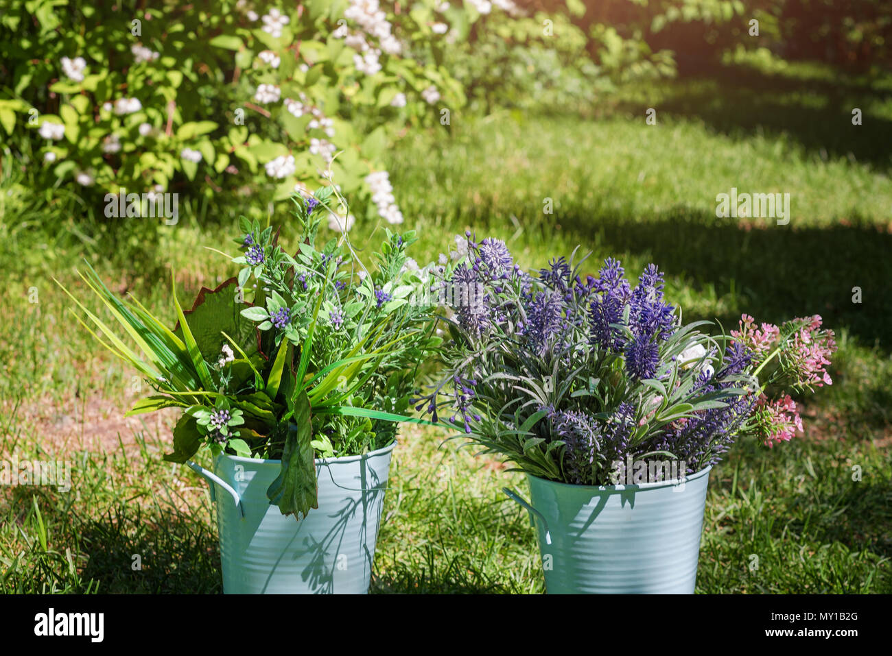 Various fresh flowers arrangement in metalic buckets in the garden