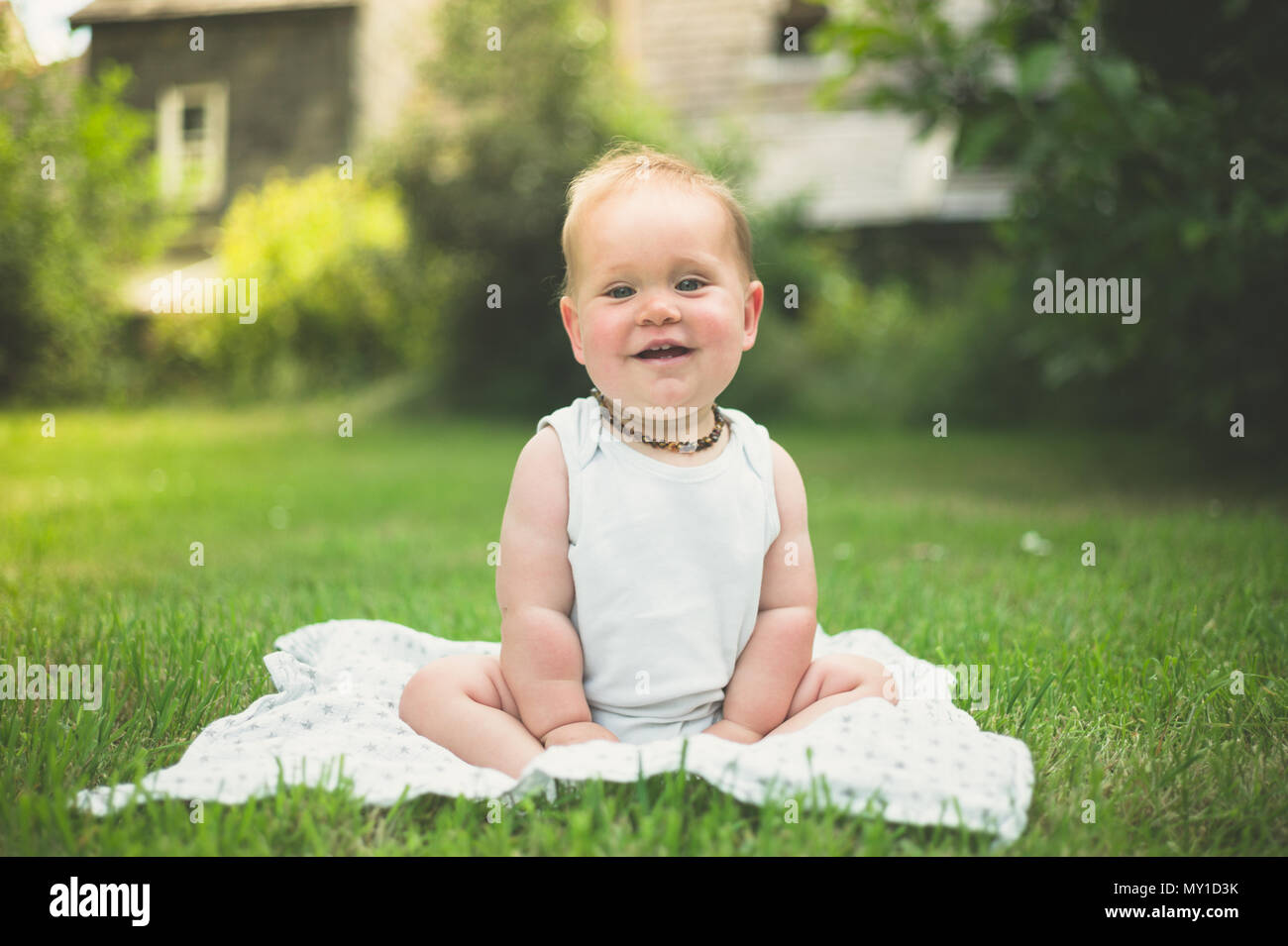 A cute little baby is sitting on the grass outside in the park Stock ...