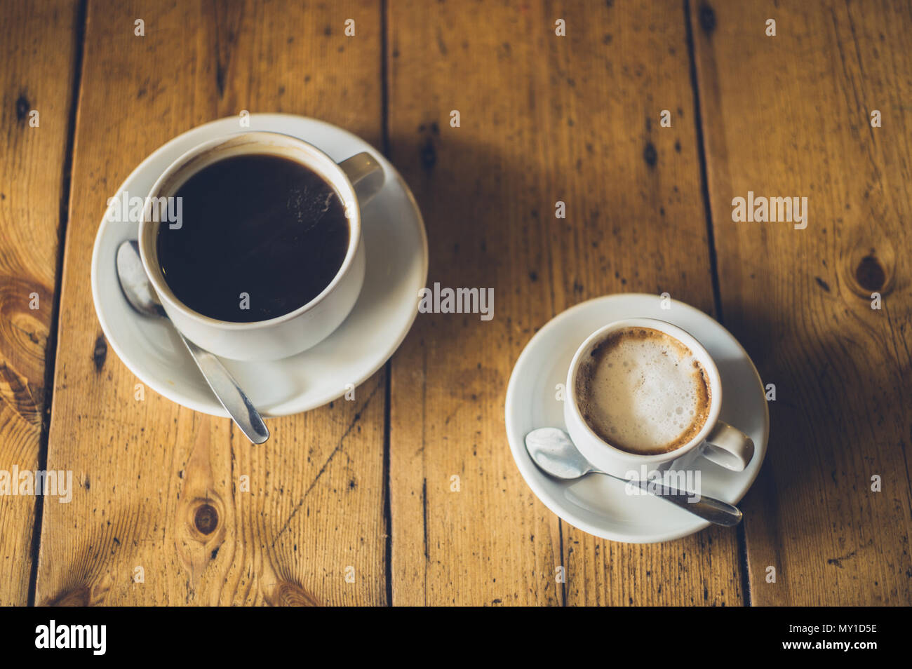 A cup of black coffee and a cup of cappucino on a wooden table Stock Photo