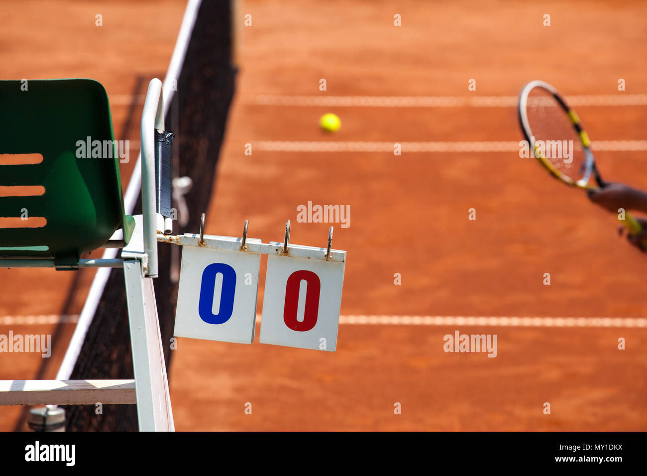 Tennis player umpire chair with scoreboard and racket on a clay court in the beginning of the game. Stock Photo