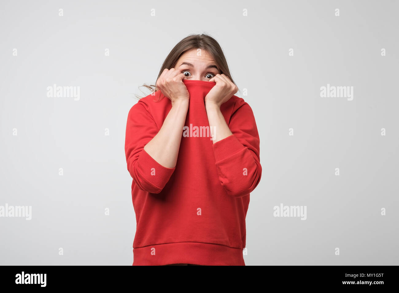 A girl with a social phobia hides her face in a sweater. Stock Photo