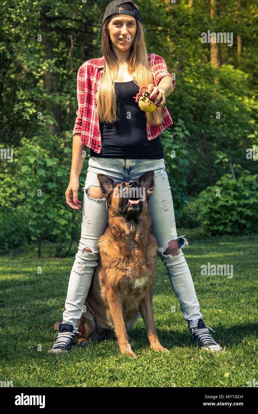 Authentic woman play with german shepherd dog in garden, toned image. Stock Photo