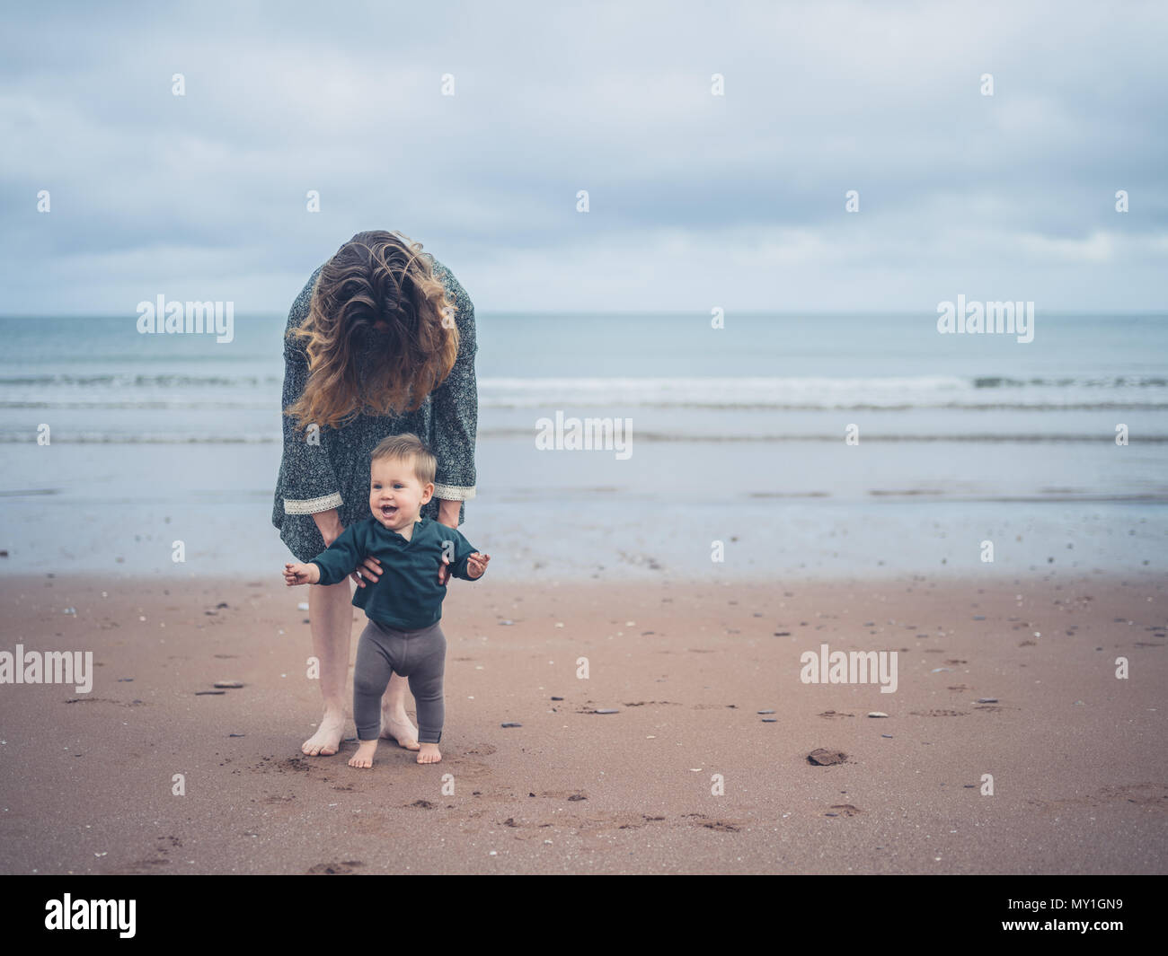 Mother helping baby to walk hi-res stock photography and images - Alamy