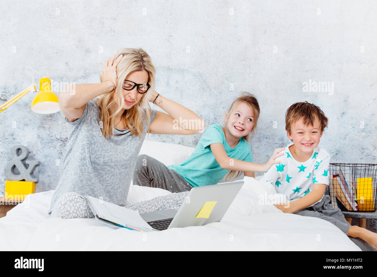 Business mum at work while her kids are playing in bed Stock Photo