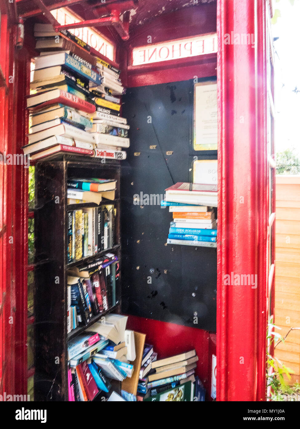 An old red telephone box used as a book swap location in a Wiltshire village. Stock Photo