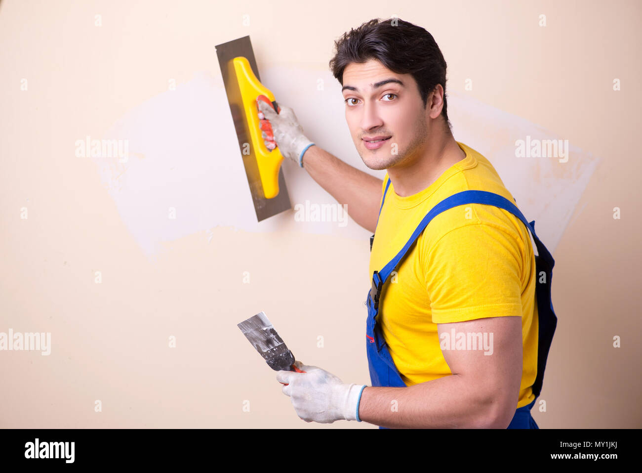 Young contractor employee applying plaster on wall Stock Photo