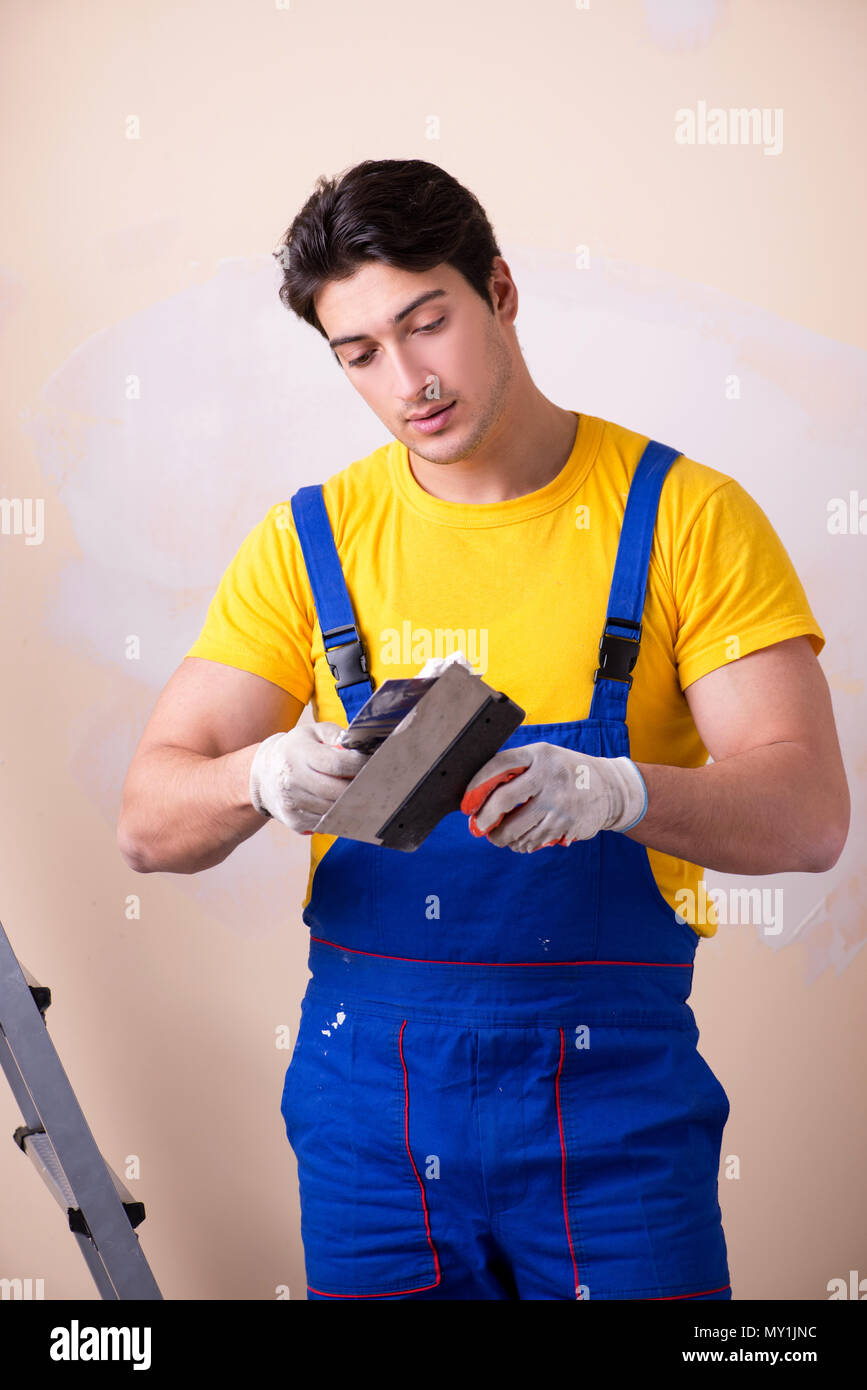 Young contractor employee applying plaster on wall Stock Photo