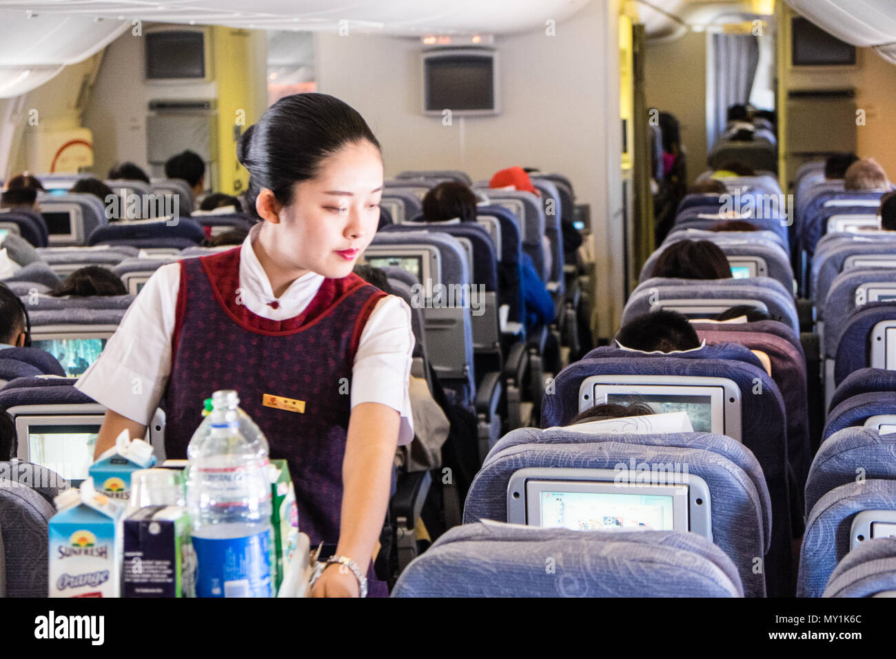Interior,inside,Air China,flight,airline,stewardess,flight,cabin,crew,serving,service,drinks,food,on,flight,from,Beijing,Asia,Asian,to,London,Europe. Stock Photo