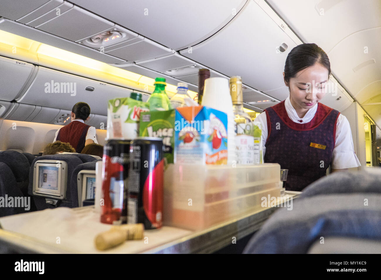 Interior,inside,Air China,flight,airline,stewardess,flight,cabin,crew,serving,service,drinks,food,on,flight,from,Beijing,Asia,Asian,to,London,Europe. Stock Photo
