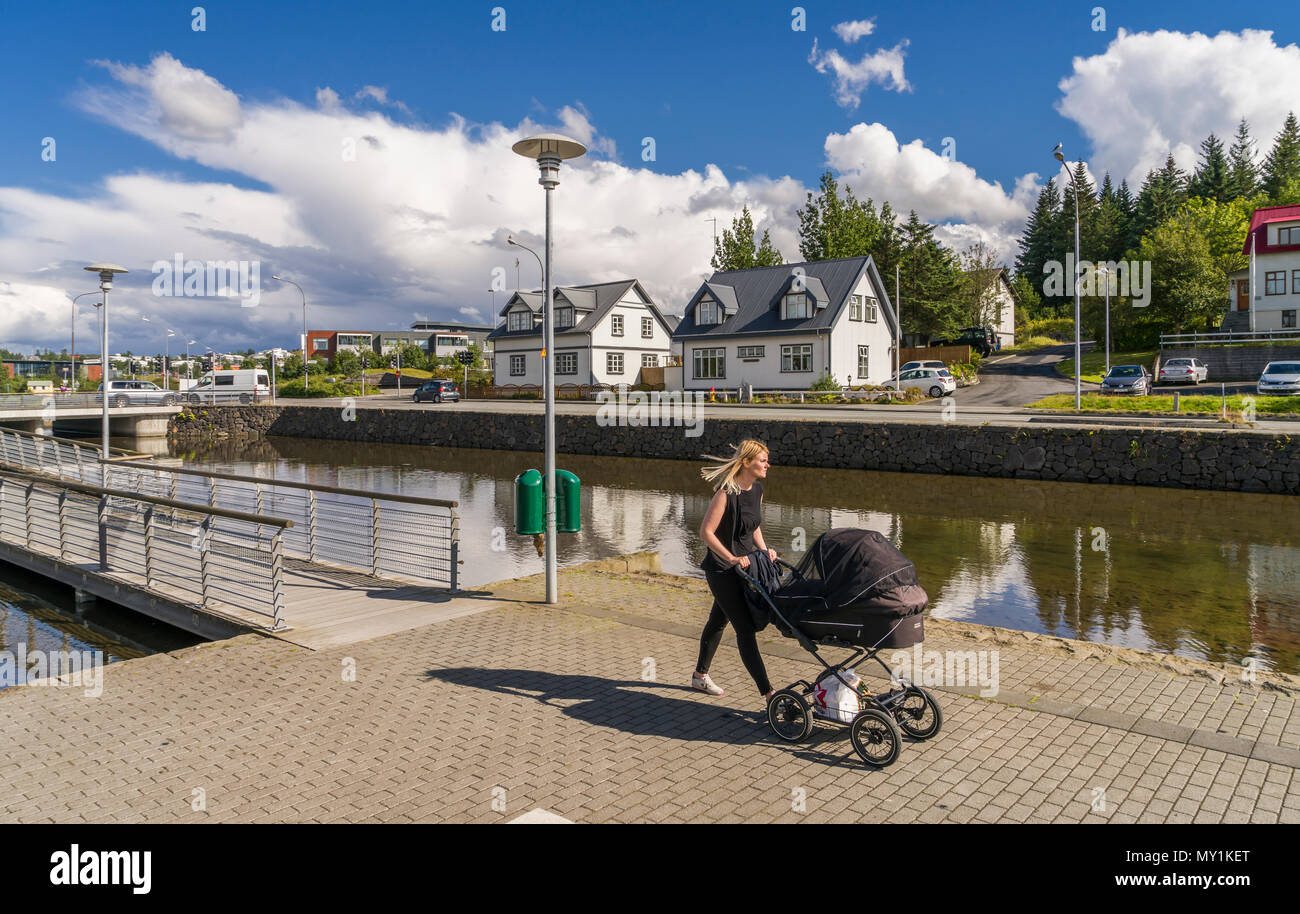 Woman with a baby carriage, Hafnarfjordur, suburb of Reykjavik, Iceland Stock Photo