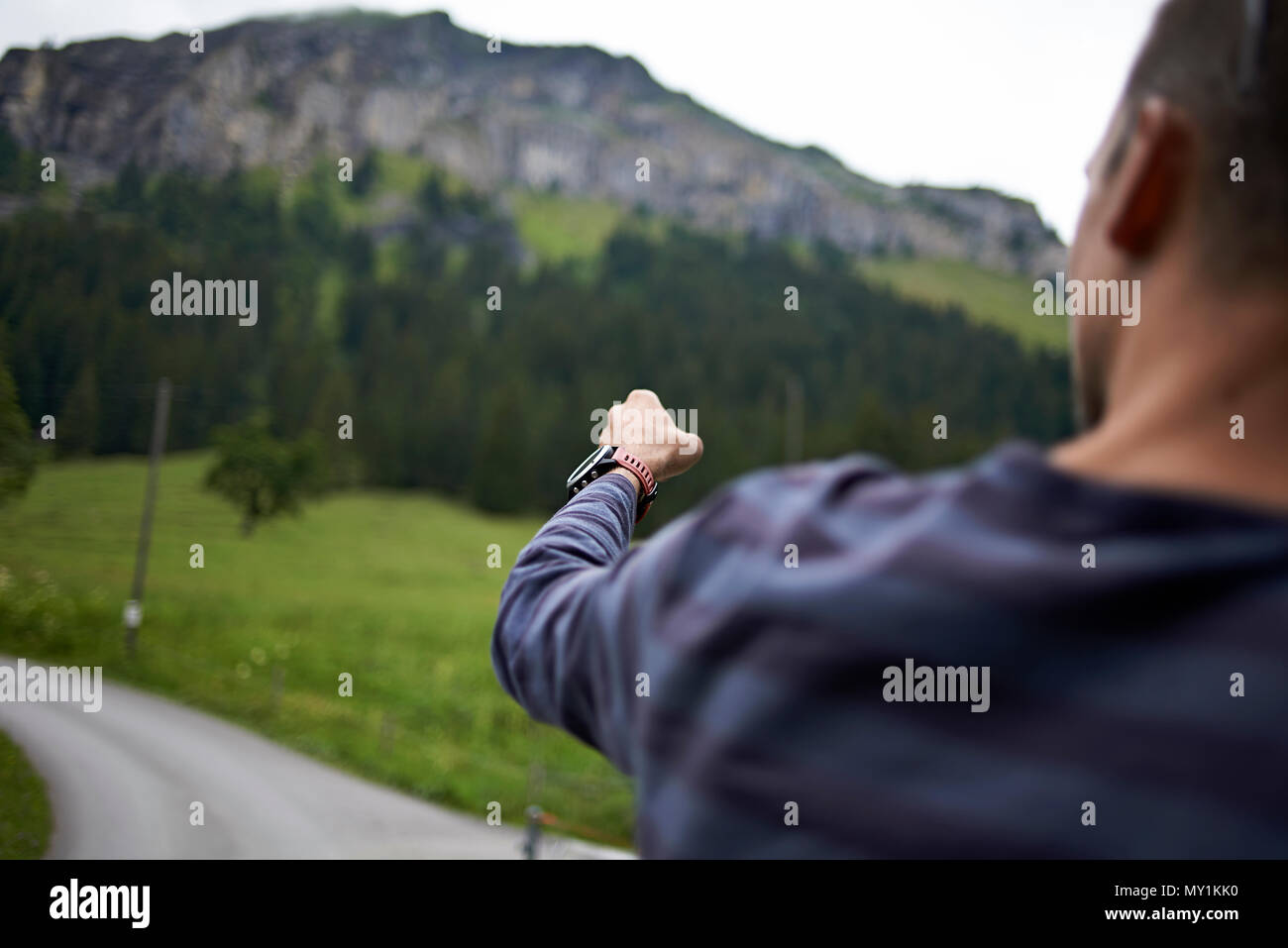 Sporty caucasian man shot from behind pointing towards a path in the mountains giving directions Stock Photo