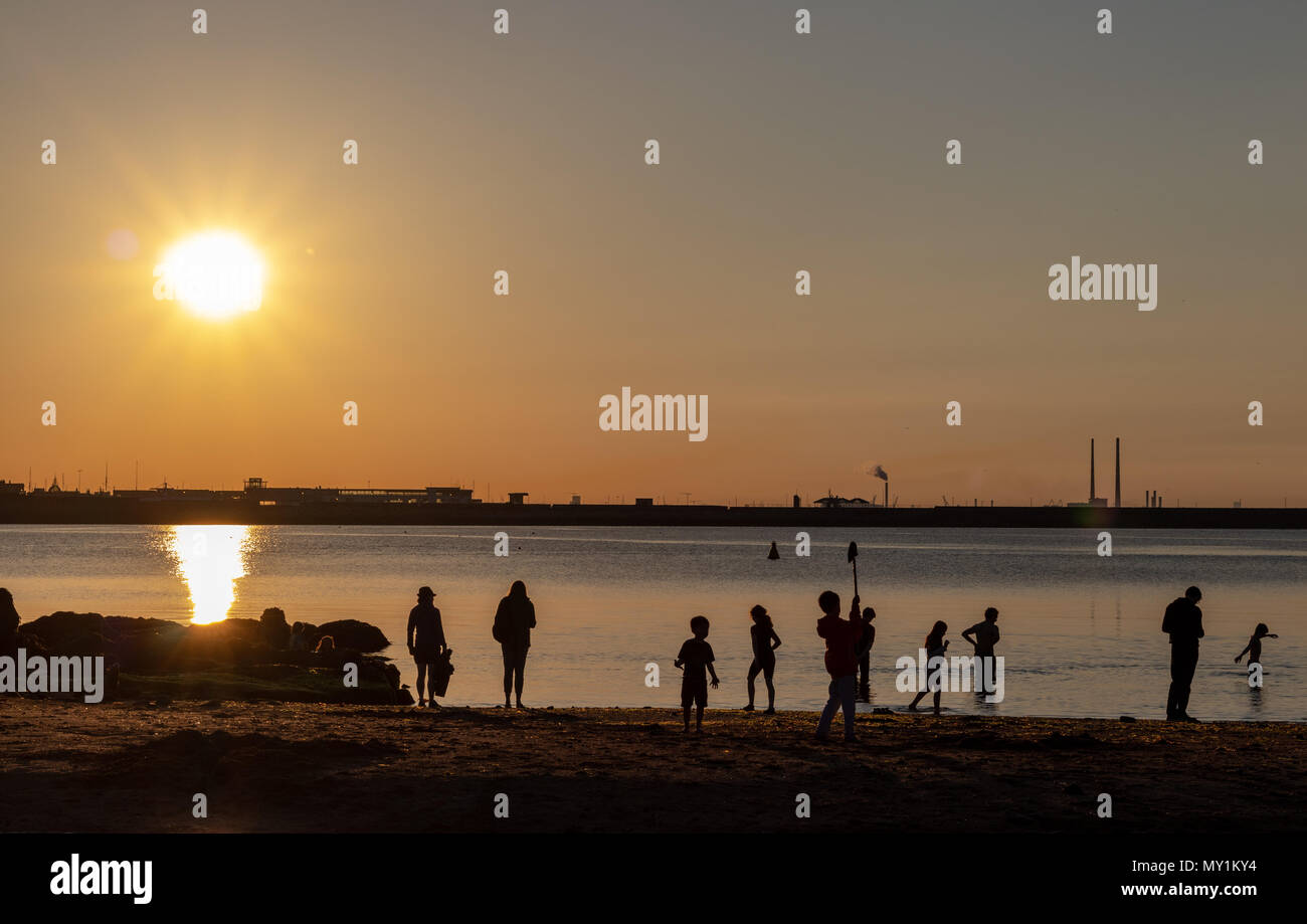 Random people standing in the Sunset, on a beach. Stock Photo