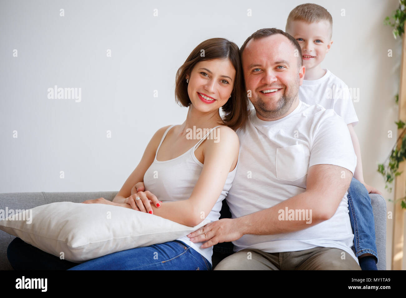 Portrait of cuddling parents with son sitting on sofa Stock Photo - Alamy