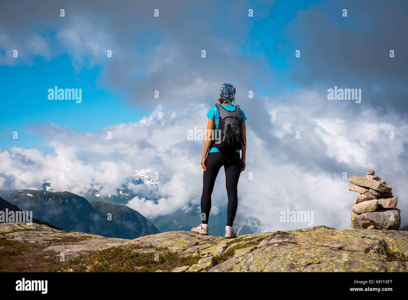 Young woman with backpack standing on fjord coast Stock Photo