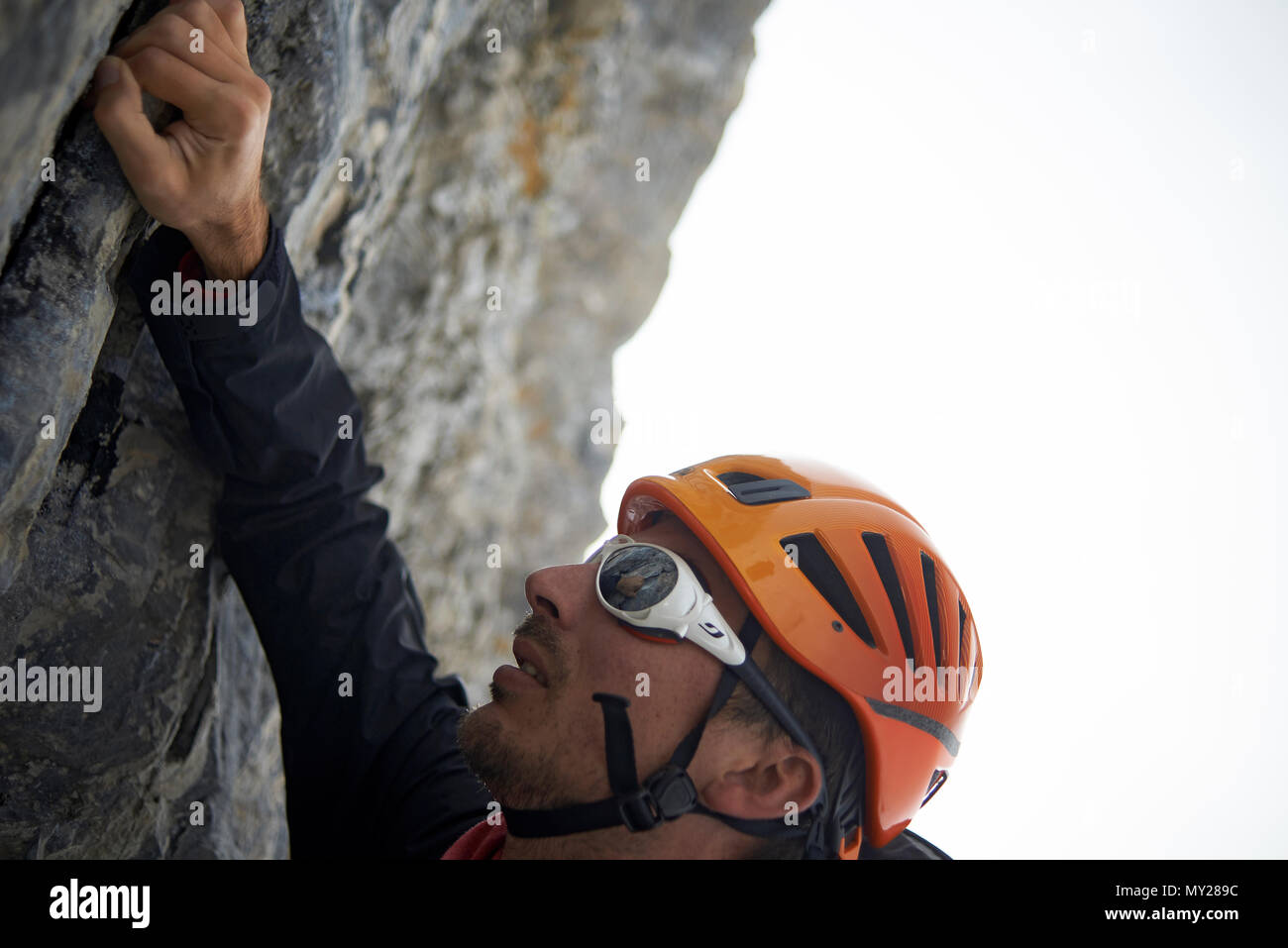 Mountaineer climbing a rock to reach the top of a mountain at high