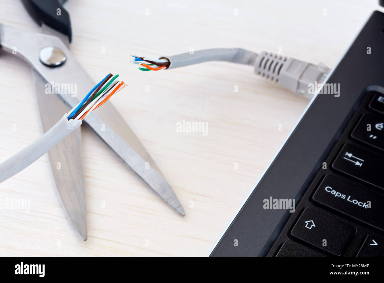 Internet cable connected to a laptop computer cut by a scissors. Concept of internet ban, cencorship and interruption. Stock Photo