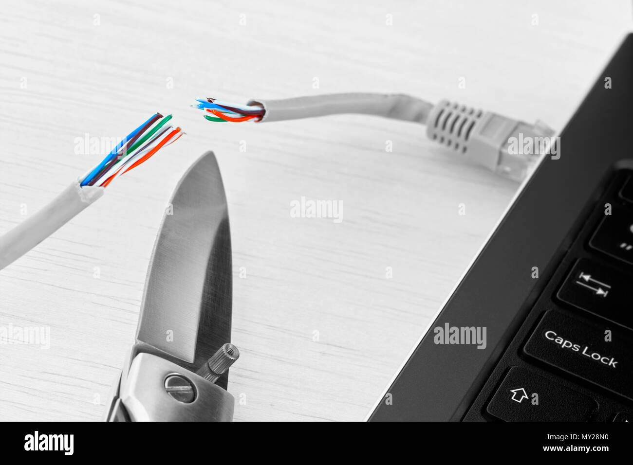 Internet ban, cencorship and interruption. Internet cable connected to a laptop cut by a pocket knife. Stock Photo