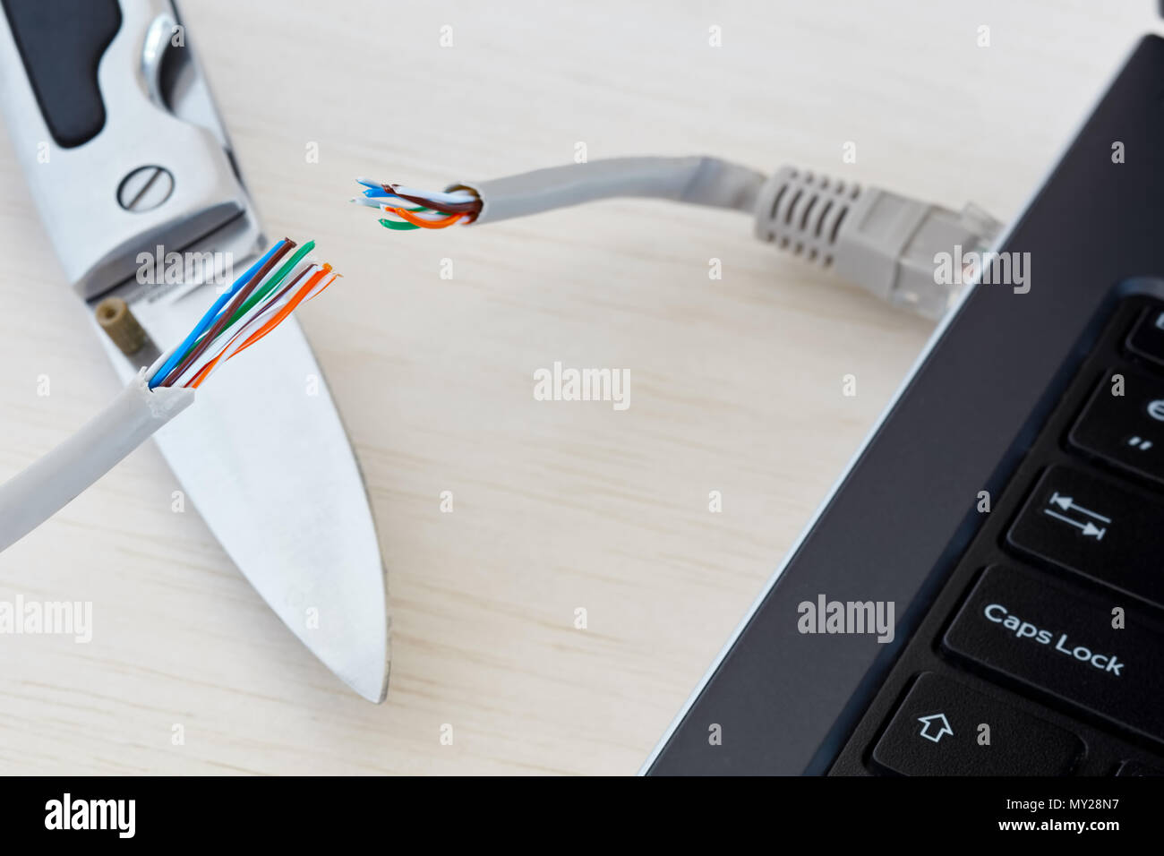 Internet ban, cencorship and interruption. Internet cable cut by a pocket knife. Stock Photo