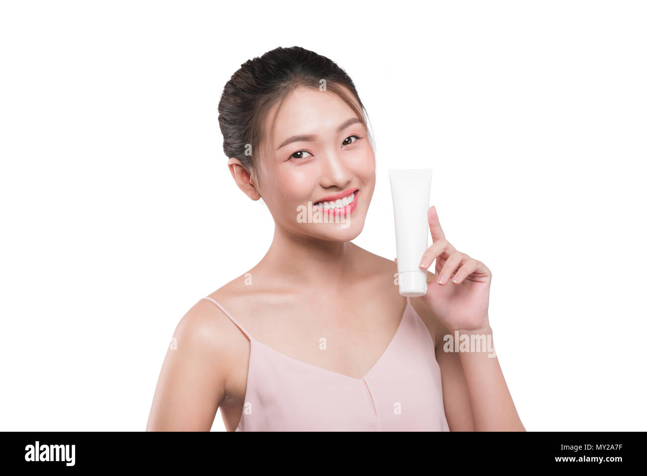 Asian young woman holding tube of moisturizer, oil, wellness, exfoliator, peeling cream in hand. Stock Photo