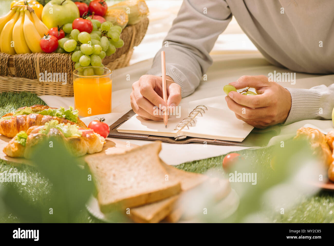 Picnic wicker basket with food, bread, fruit and orange juice on a red ...