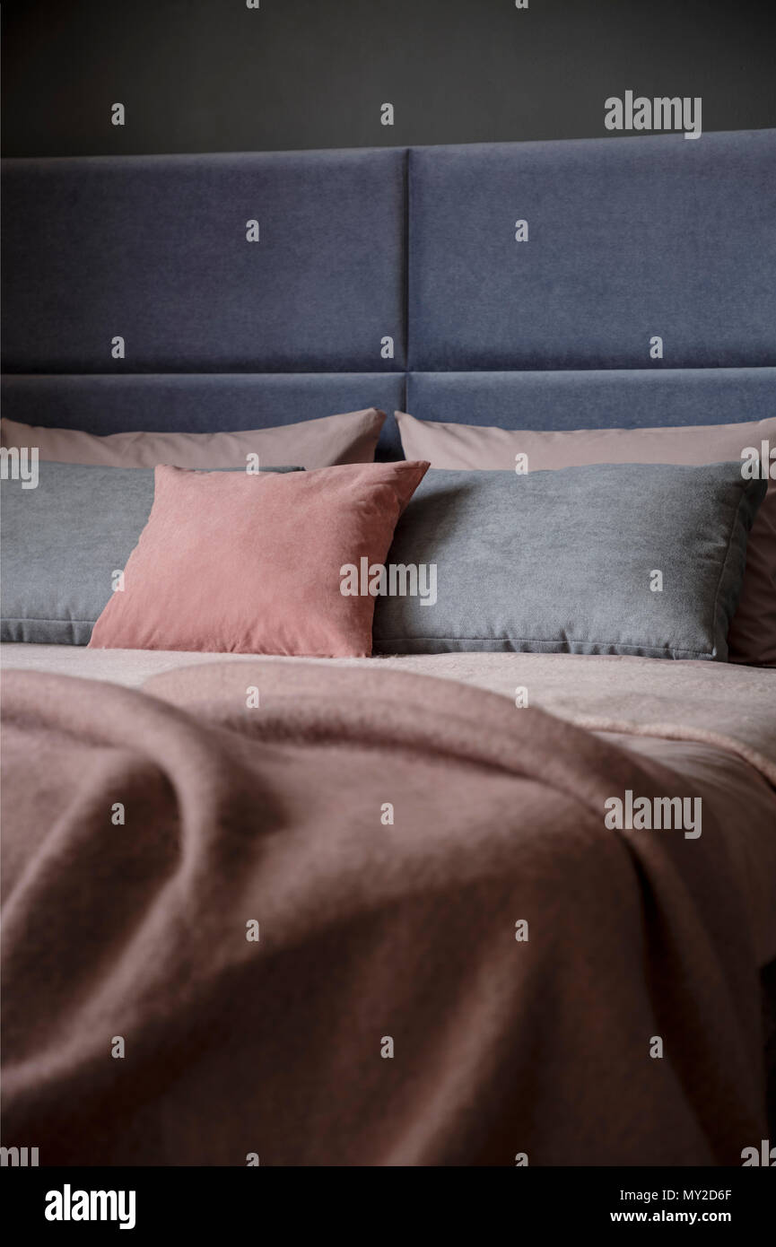 Grey and pink pillow on bed with headboard in woman's bedroom interior