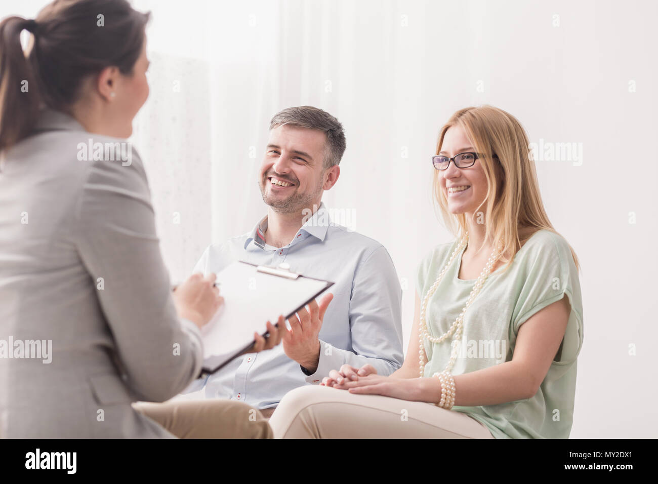 Psychotherapist analyzing a young, happy married couple in a bright office Stock Photo