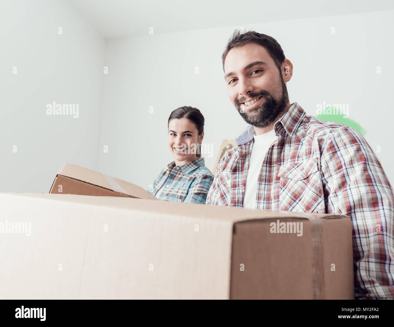 Young smiling couple moving into a new house, they are carrying full ...