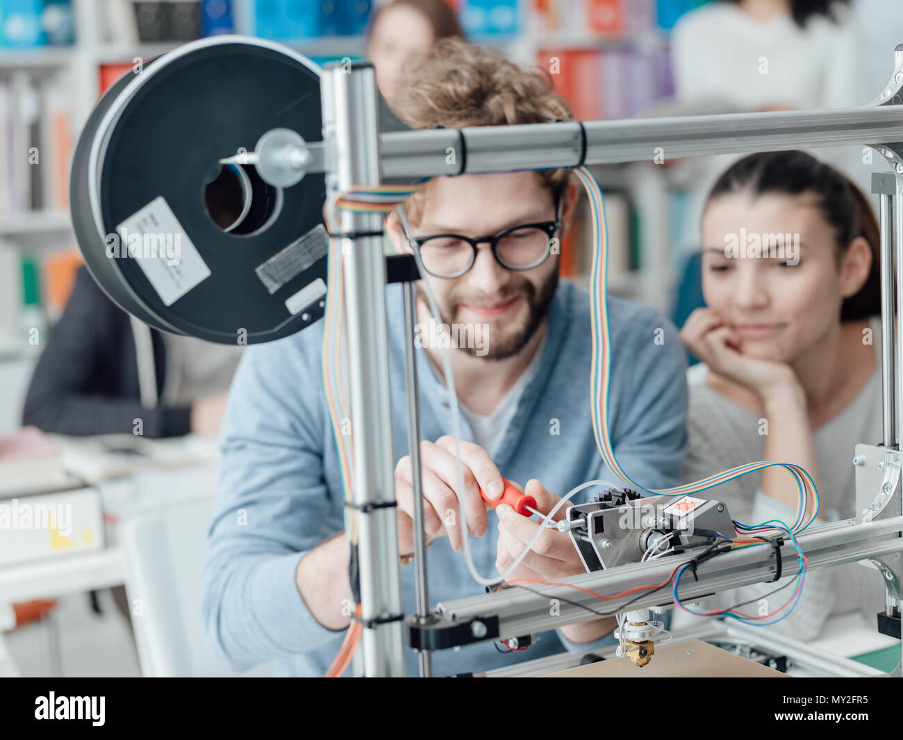 Engineering students using a 3D printer in the laboratory, a student is using a screwdriver Stock Photo