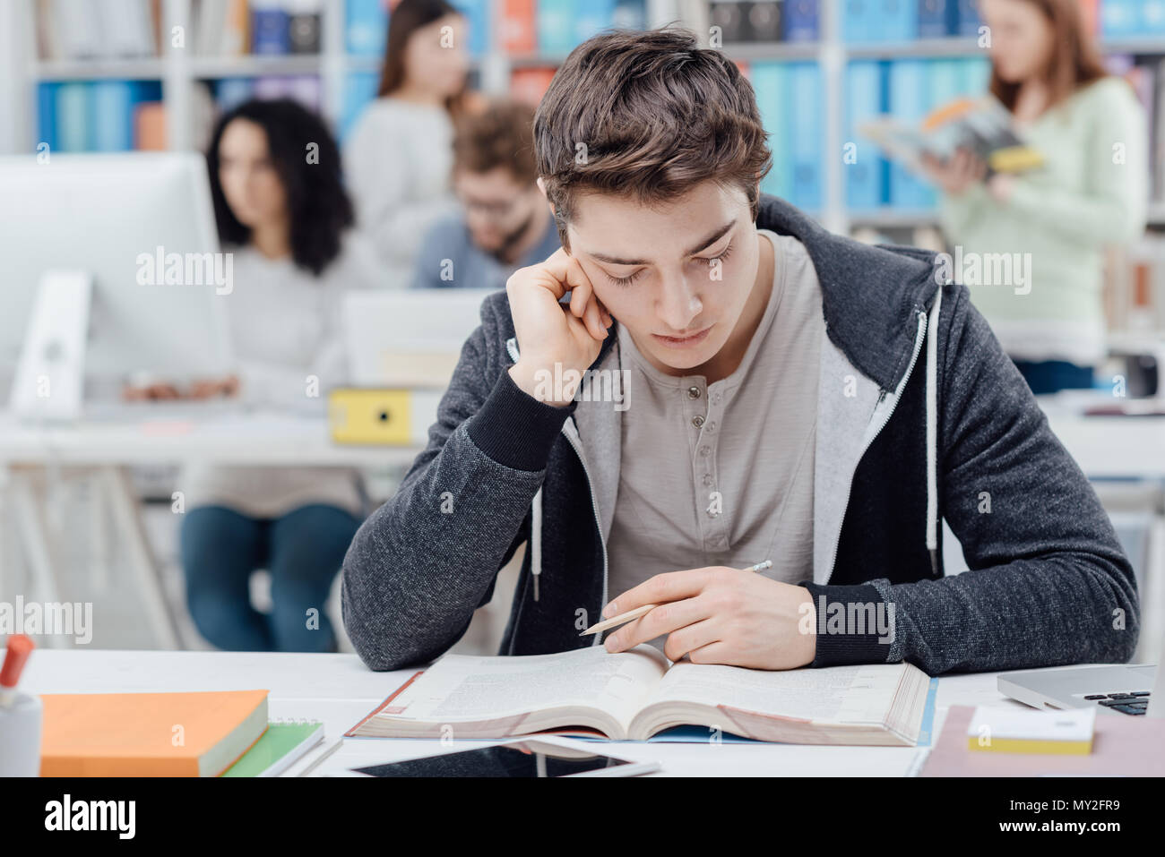 College Student Sitting At Desk And Studying A Book Group Of