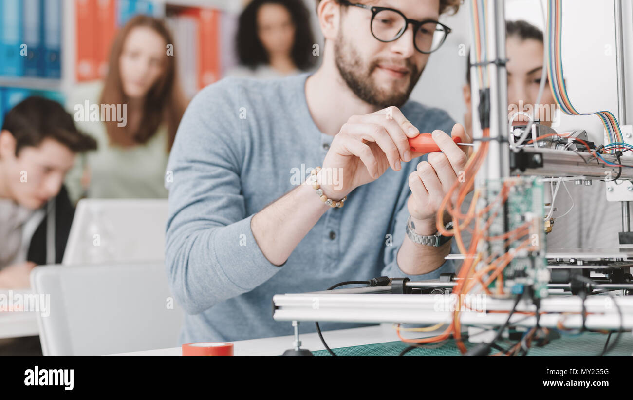 Engineering students using a 3D printer in the laboratory, a student is using a screwdriver Stock Photo